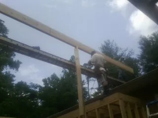Carpenter setting a ridge beam over a new addition frame — Ice Dam Removal by Roofing Brothers in Enigma