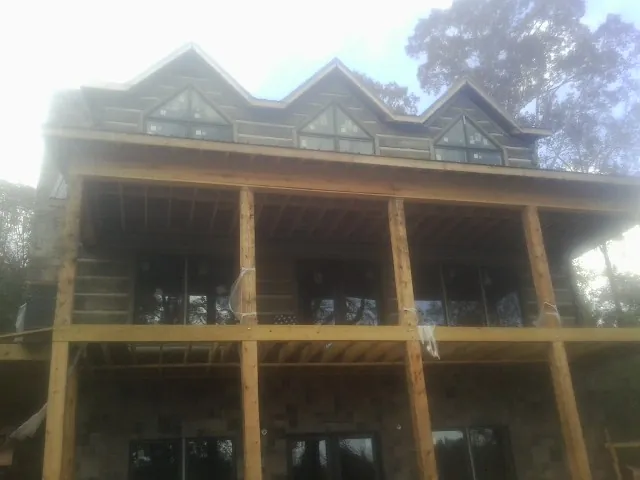 Dormers and porch framing on a large log home under construction — Roof Coating work by our crew in Enigma
