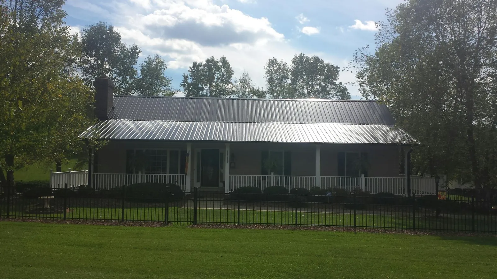 Gray metal roof on a brick ranch with a full width front porch — Gutter Guard Installation work by our crew in Enigma