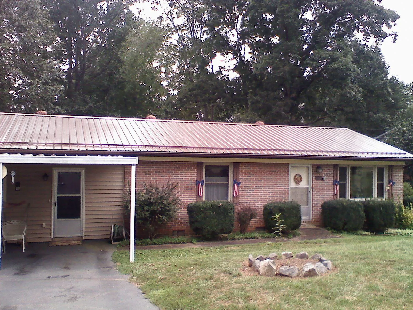Bronze metal roof and carport on a brick ranch home — Roof Repair work by our crew in Enigma
