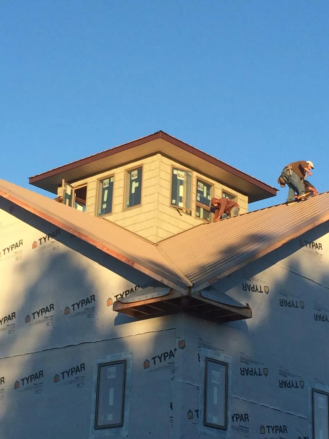Roofers working around a rooftop cupola on a new metal roof at sunset — Roof Waterproofing in Enigma by Roofing Brothers
